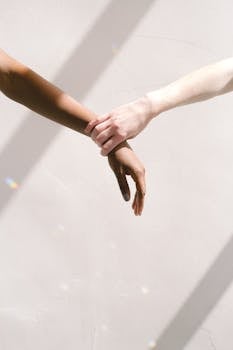 Two people of different ethnic backgrounds holding hands, symbolizing unity and support.